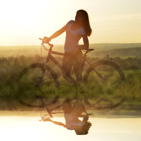 Girl with bicycle in the sunsetの写真素材