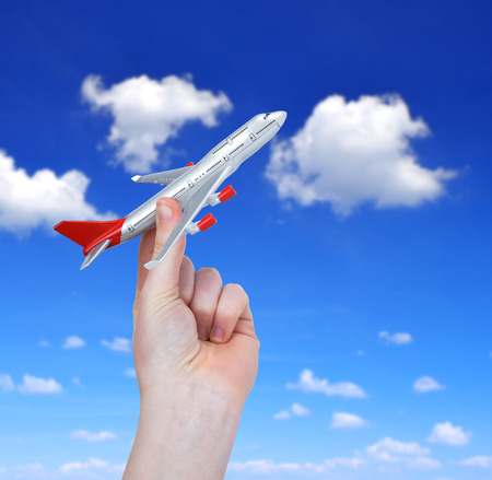 Hand holding the toy plane against cloudy skyの写真素材