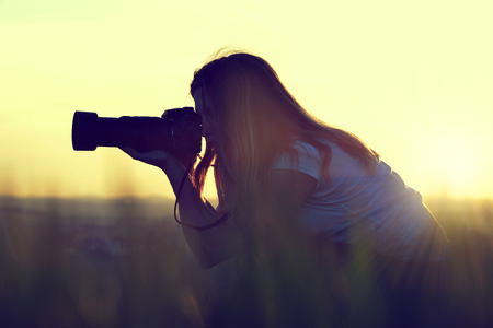 Photographer taking pictures with SLR camera at sunsetの写真素材