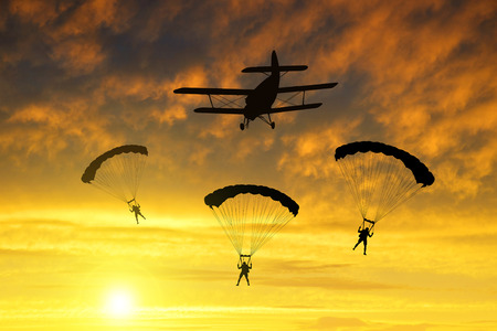 Silhouette skydiver parachutist landing at sunset