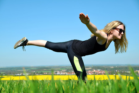 Young woman stretching on a meadow in sunny day.の写真素材