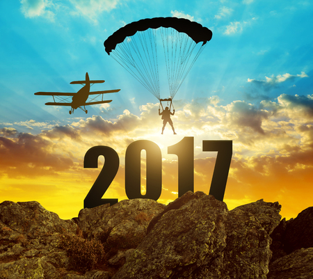 Silhouette skydiver parachutist landing in to the New Year 2017 at sunset