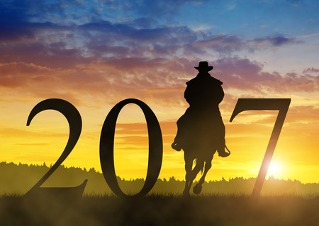 Silhouette of a cowboy riding a horse in the sunset. Forward to the New Year 2017の写真素材