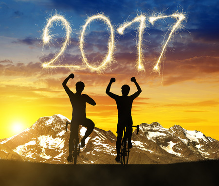 Two cyclists on bicycle at sunset. Forward to the New Year 2017