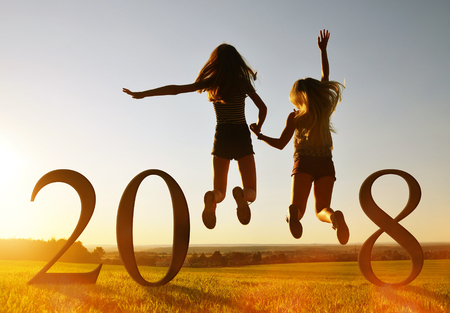 Silhouette of girls jumping up in the sunset at the celebration of New Year 2018.の写真素材
