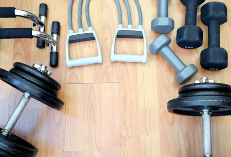 Dumbbells and elastic exercise band for fitness training on wooden background.の写真素材