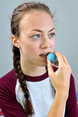 Young girl applying hygienic lip balm. Skin care concept.の写真素材