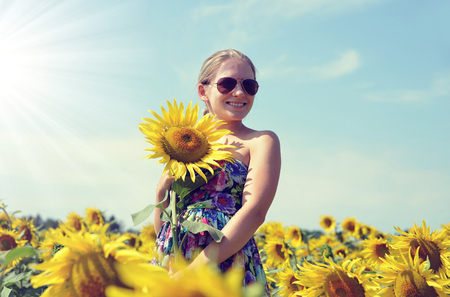 Beautiful girl in the sunflower field. Summer lifestyle concept.の写真素材