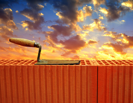 Trowel on brick wall in sunset. Masonry tools.の写真素材