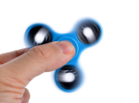 Palying with a blue Fidget Spinner isolated on white backgroundの写真素材
