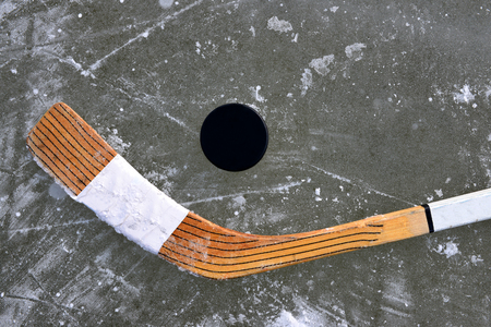 Black puck and hockey stick lying on a ice rink.の写真素材