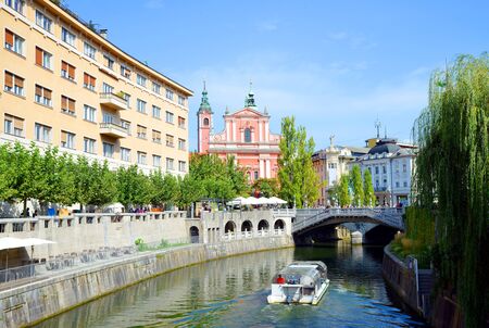 LJUBLJANA, SLOVENIA - September 08, 2018: Franciscan Church of the Annunciation and river Ljubljanica with an excursion boat in the city of Ljubljana.のeditorial素材