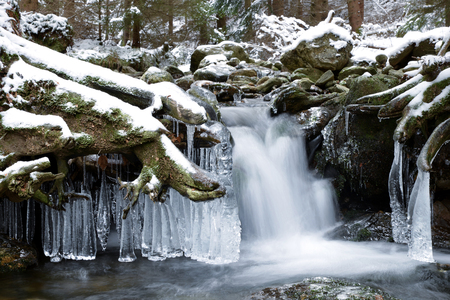 Waterfall with ice crystals forming on a winter mountain creek.の写真素材