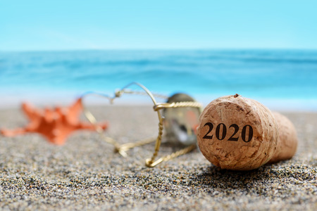 Cork stopper of champagne with number 2020 and starfish on sand beach. Happy New Year concept.の写真素材