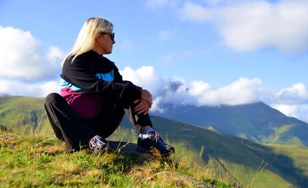 Woman sitting on mountain meadow over village of Pla d'Adet in French Pyrenees.の写真素材