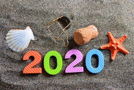 Number 2020, sea shell, starfish  cork stopper of champagne on the sand beach. Happy New Year.の写真素材