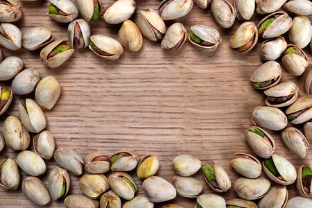 Frame from salted pistachio nuts on wooden board.の写真素材