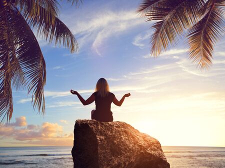 Silhouette of a woman practicing yoga on a tropical beach. Healthy lifestyle theme.の写真素材