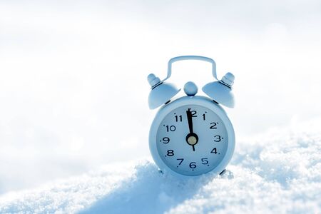 Small alarm clock in snow with copy space for your text.の写真素材