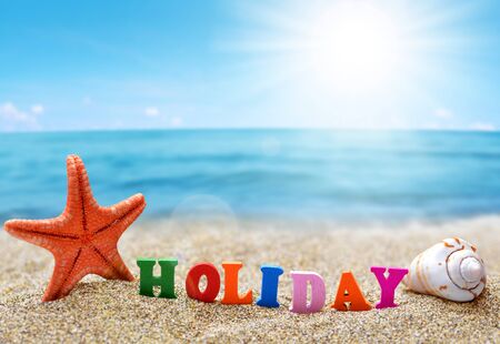 Colorful word Holiday and sea shell with starfish on the tropical sand beach. Summer vacations concept.の写真素材