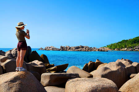 Girl photographing the beautiful coast of the tropical island of La Digue, Indian Ocean, Seychelles.の写真素材