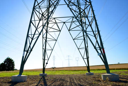 Electric pylon on field. Transmission tower with sunny sky at the background.の写真素材