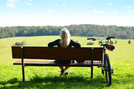 A female cyclist relaxing on a bench after a ride in nature.の写真素材