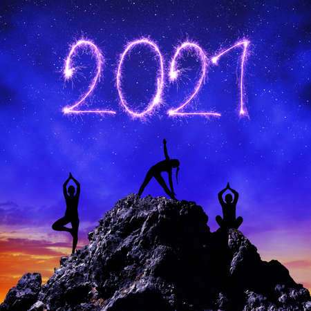 Silhouette of a girls practicing yoga on rock in the New Year 2021.の写真素材