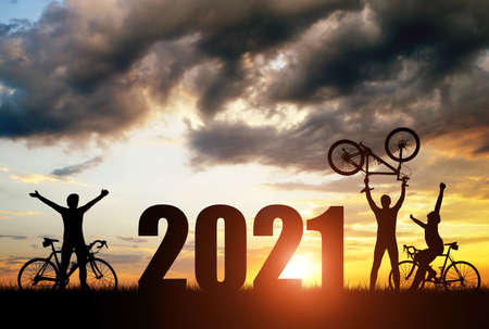 Silhouette of cyclists with bicycles at sunset. Forward to the New Year 2021. Holiday concept.の写真素材