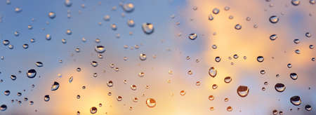Water drops on a window glass after the rain at sunset. Panoramic nature background.の写真素材