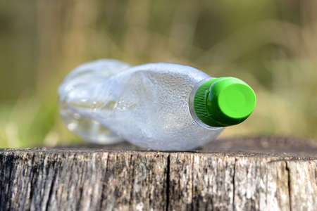 Plastic bottle on a tree stump. Pollution garbage in forest. Concept of nature conservation.の写真素材