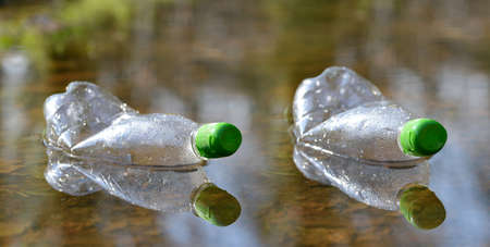 Plastic bottles floating in puddle of water. Pollution garbage in forest. Concept of nature conservation.の写真素材