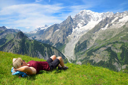 Tourist lying on a meadow in sunny day, at the background Mont Blanc (Monte Bianco) mountain range. Aosta valley, Italy.の写真素材