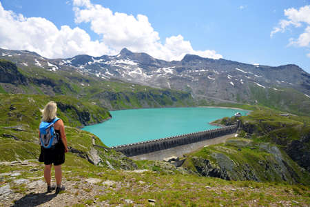 Hiker by the mountain lake Lac de Goillet, Aosta valley, Italy. Summer landscape in the Alps.の写真素材