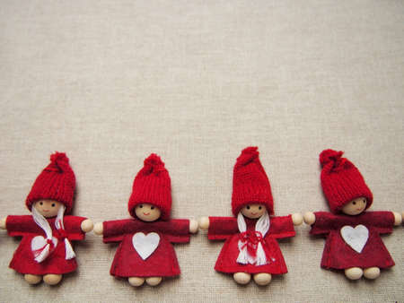 christmas card, four little red elfs with white heart on dress and knitted hat on gray background, winter background wallpaperの写真素材