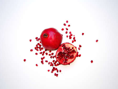 christmas decoration background for greeting card, red pomegranate fruit, whole fruit and sliced in half, red pomegranates in detail, close-up, white backgroundの写真素材