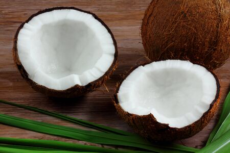 Fresh coconut - green leaves on wooden background - close up