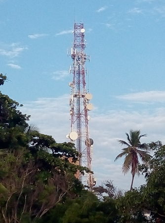 Telecommunication tower in the blue sky. Cellphone telecommunication tower with clouds and blue sky