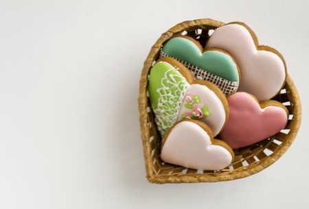 gingerbread in pink glaze. Bakery products. Gingerbread in the shape of a heart. Place for text. Gingerbread pattern Background. Painted gingerbread in a straw basket.の写真素材