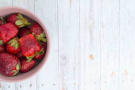 Sweet, juicy, ripe strawberries. Red, large strawberries in a pink cup. Food with vitamins. Vegetarian food.A cup with strawberries on a wooden light background, there is a place for text.の写真素材