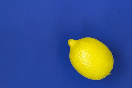 One yellow lemon on a blue background, there is a place for text. Fruits and vitaminsの写真素材