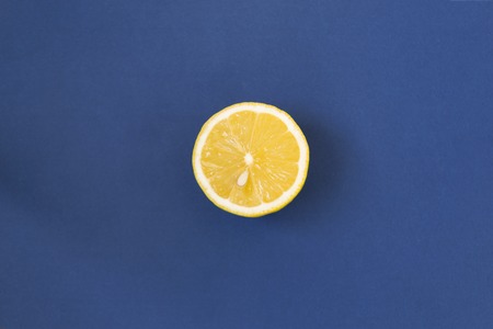 Half and whole a juicy lemon on a blue background with shadow and copy space. Ingredient for drink. Top viewの写真素材