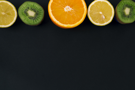 Multivitamins. Background of orange, lemon and kiwi. Fruit on a black background. There is a place for text.の写真素材