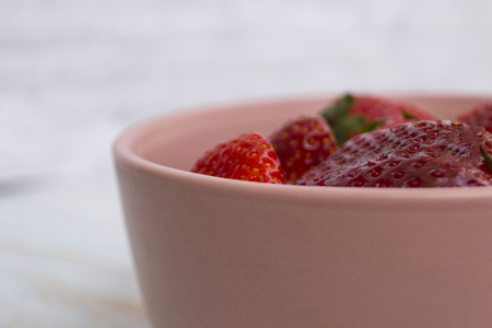 Red strawberry in a pink bowl on a light background. There is a place for text.の写真素材