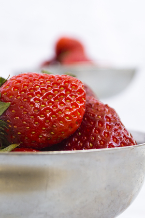 Bright ripe strawberry in a metal cups on a light background. Square. Soft focus. Vegetarianism, healthy lifestyle.の写真素材