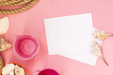 Summertime marine vacation background with lots of seashells, pebbles, nautical rope on pink background. There is a sheet of paper for text, congratulations, inscriptions. Marine conceptの写真素材