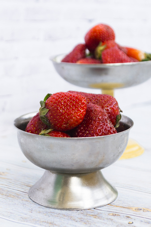 Bright ripe strawberry in a metal cups on a light background. Square. Soft focus.の写真素材