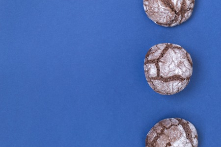 Flat chocolate marble cookies lay on blue paper. Chocolate cookie shot. There is a place for text.の写真素材