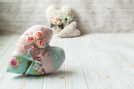 Three textile hearts with a romantic flower color on a simple light wooden background. selective focus. There is a place for text. Shabby chic style.の写真素材