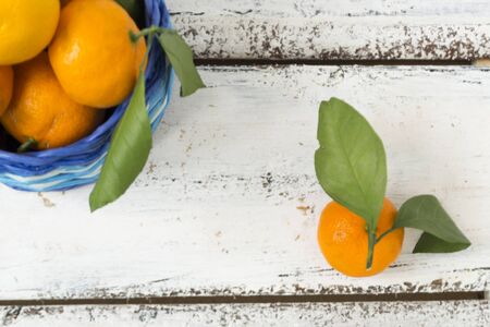 Tangerines , oranges, clementines, citrus fruits, with green leaves lie in a wicker basket on a wooden background with copy space. View from above. Christmas concept.の写真素材